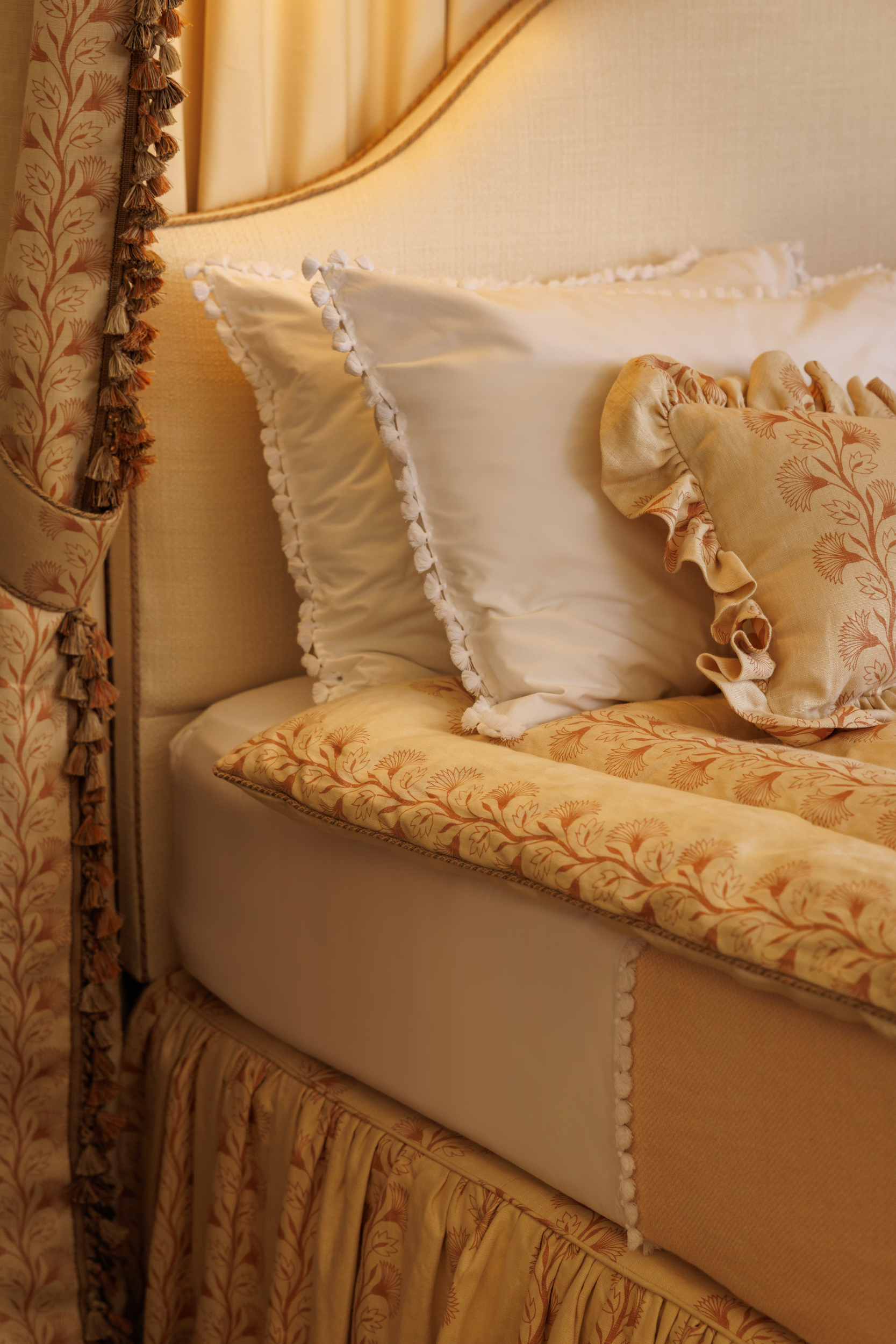 Close up of a beautiful bed, with coordinating floral linen fabric across valance, eiderdown, half tester and cushion